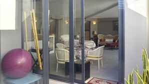 Ein Zimmer mit Glastür, das in einen Essbereich mit Korbmöbeln und einem Tisch führt.