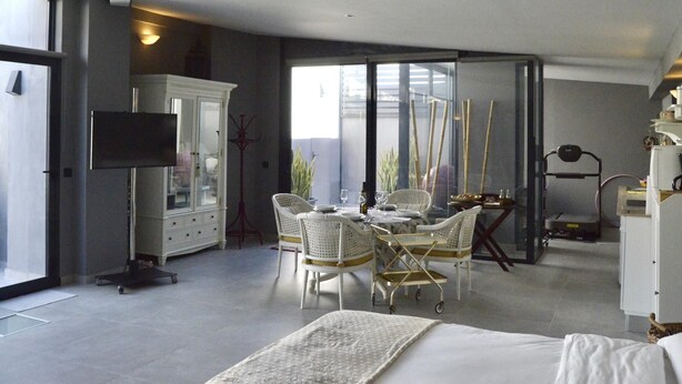 Ein modernes Hotelzimmer mit Bett, Esstisch mit Stühlen, Fernseher und großem Fenster mit Blick.
