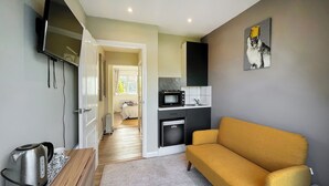 Een kleine leefruimte met een bank, kitchenette en een televisie.