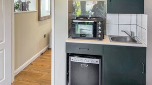 Een kleine keuken met een inbouwoven, een magnetron en een spoelbak.