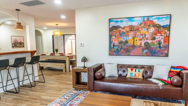 A modern living room with a brown leather sofa, a coffee table, and a colorful rug. - Agave Azul Villa | Monthly/Weekly Discounted Rates (Clinton)