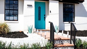 A white building with a turquoise door, numbered 1300B, and a red-tiled roof. - Spacious 3BR Home in Clinton. Weekly & Monthly Discounts Available! (Clinton)
