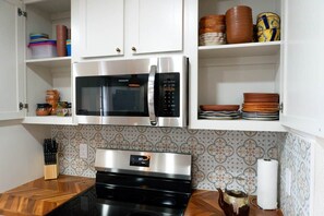 A kitchen with a stainless steel microwave, oven, and a set of knives on the counter. - Agave Azul Villa | Monthly/Weekly Discounted Rates (Clinton)
