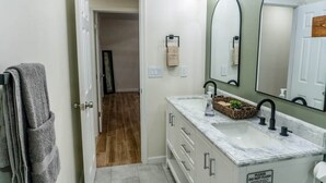 A bathroom with a white vanity, a large mirror, and a towel rack. - Agave Azul Villa | Monthly/Weekly Discounted Rates (Clinton)
