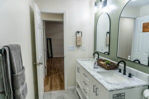 A bathroom with a white vanity, a large mirror, and a towel rack. - Agave Azul Villa | Monthly/Weekly Discounted Rates (Clinton)
