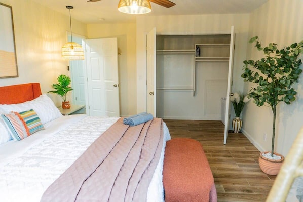 A bedroom with a bed, bedside table, and a potted plant.