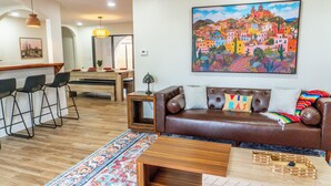 A living room with a brown leather sofa, a colorful painting, and a wooden coffee table. - Spacious 3BR Home in Clinton. Weekly & Monthly Discounts Available! (Clinton)