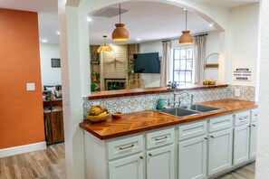 A kitchen with a wooden countertop, white cabinets, a built-in oven, and a large window. - Agave Azul Villa | Monthly/Weekly Discounted Rates (Clinton)