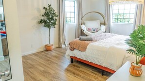 A bedroom with a bed, a hanging chair, a potted plant, and a window. - Agave Azul Villa | Monthly/Weekly Discounted Rates (Clinton)