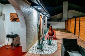 An outdoor patio area with a brick wall, a grill, and a seating area with a table and chairs. - Agave Azul Villa | Monthly/Weekly Discounted Rates (Clinton)
