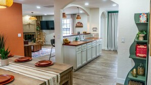 A modern kitchen with white cabinets, a wooden countertop, and a dining area with a table set for four. - Agave Azul Villa | Monthly/Weekly Discounted Rates (Clinton)