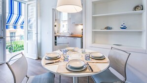 A dining area with a round table set for four, a hanging light fixture, and a view of the outside balcony. - Nice apartment for 4 guests with A/C, WIFI, TV and balcony (Cecina)