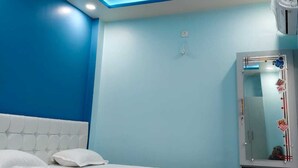 A bedroom with a bed, a ceiling fan, a mirror, and an air conditioning unit. - Viraj Homestay (Varanasi)