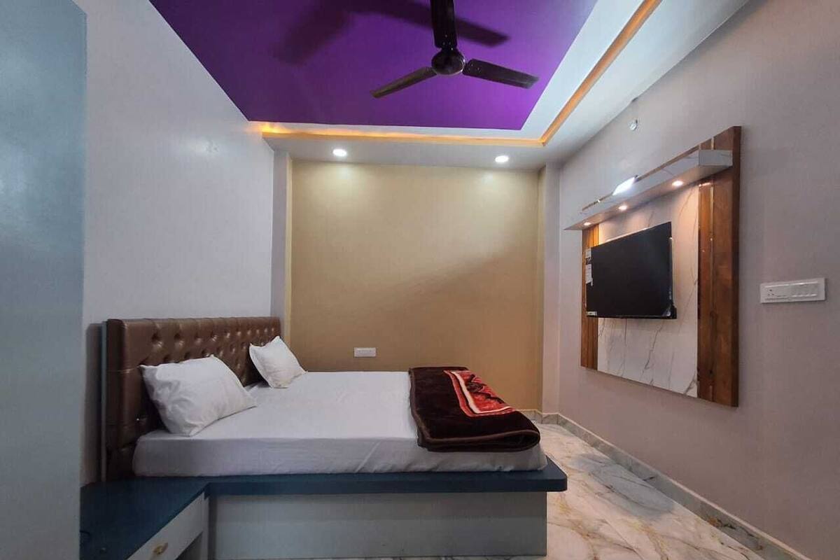A bedroom with a bed, a ceiling fan, recessed lighting, a flat-screen TV, and a marble floor.