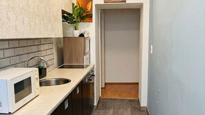 A kitchen with a microwave, sink, cabinets, and a potted plant. - Cozy Convenient Room Prime Location (Vienna)