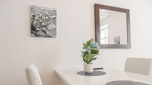 A white dining table with a potted plant, a mirror, and a framed artwork on the wall. - Cozy Convenient Room Prime Location (Vienna)