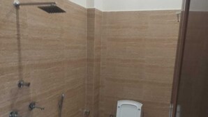 A small, compact bathroom with a toilet, shower, and sink. - Hotel Pilgriims (Varanasi)