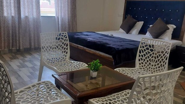 A room with a bed, a table, and four chairs. - Hotel Pilgriims (Varanasi)