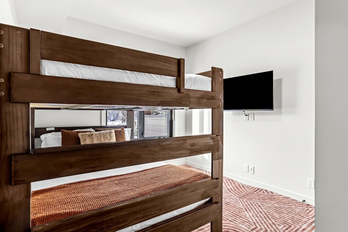 Una cama litera con un televisor montado en la pared superior.