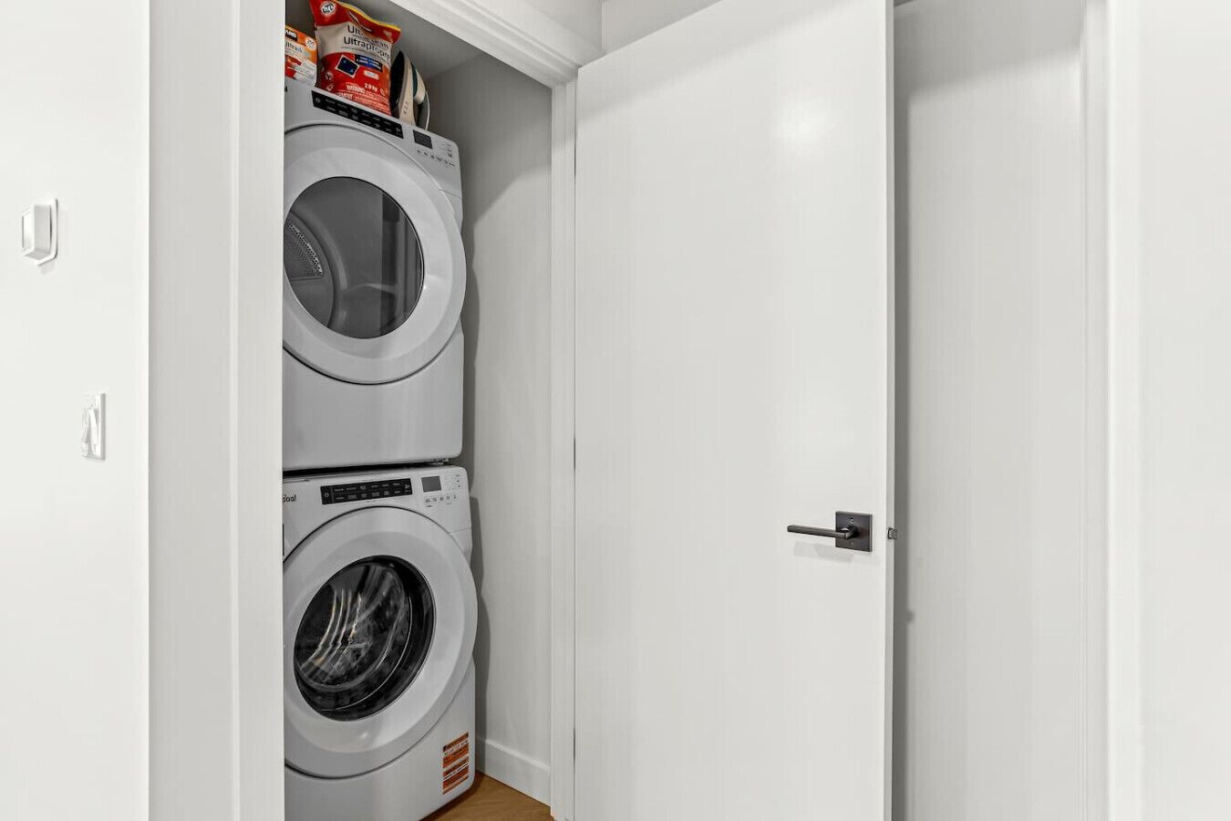 A laundry room with two stacked washing machines and a door.