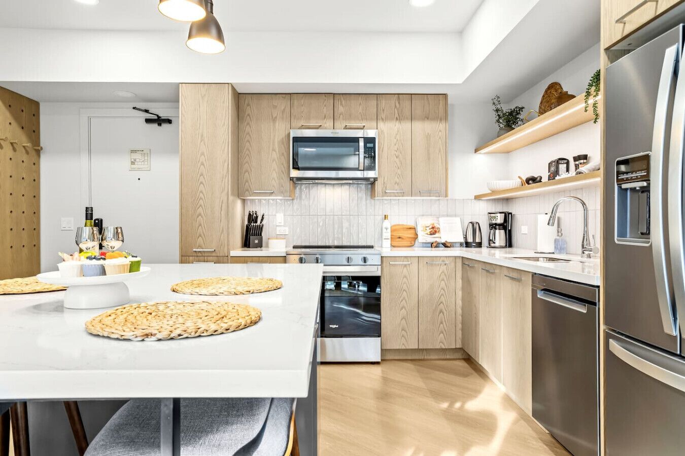 Una cucina moderna con mobili in legno, un'isola centrale, elettrodomestici in acciaio inossidabile e un forno a microonde integrato.