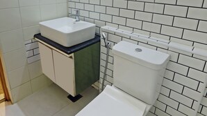 Un bagno con piastrelle bianche, un lavandino, un water e uno specchio.