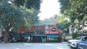 Un edificio con una tenda verde, un cartello Coca-Cola e un cartello Kingfisher.