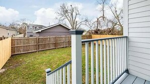 A residential backyard with a wooden fence, a grassy lawn, and a house in the background.
