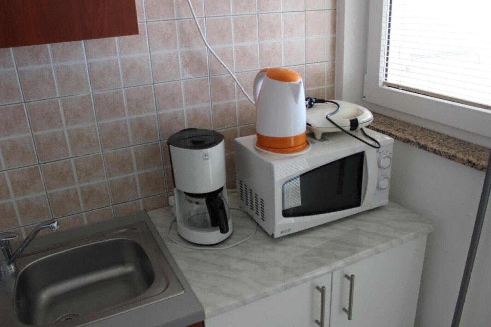 Een keuken met een koffiezetapparaat, magnetron en een spoelbak.