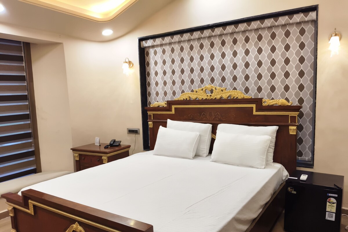 A hotel room with a large bed, a bedside table with a phone, and a nightstand.