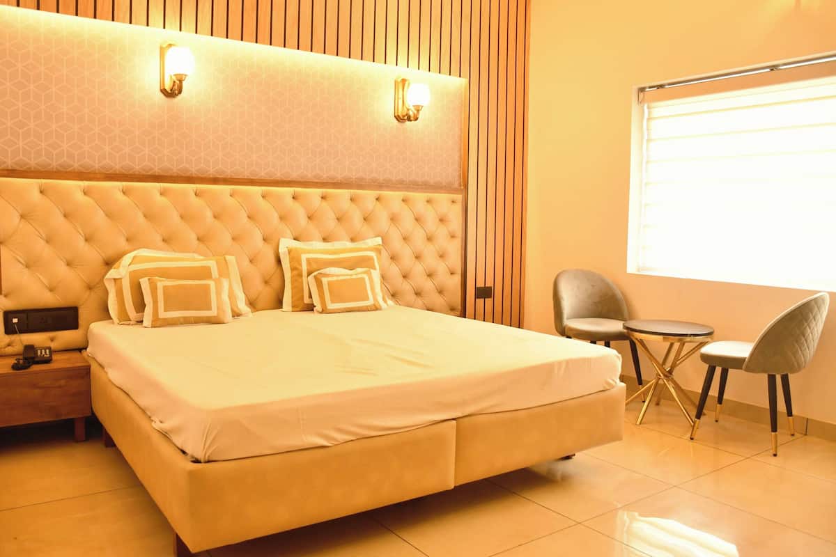 Un ampio letto con testiera imbottita, due comodini e un piccolo tavolo rotondo con sedie.