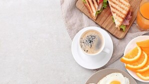 A breakfast setting with a sandwich, coffee, and orange slices. - Hotel Sona Deluxe @ 2Min From New Delhi Railway Station (New Delhi)