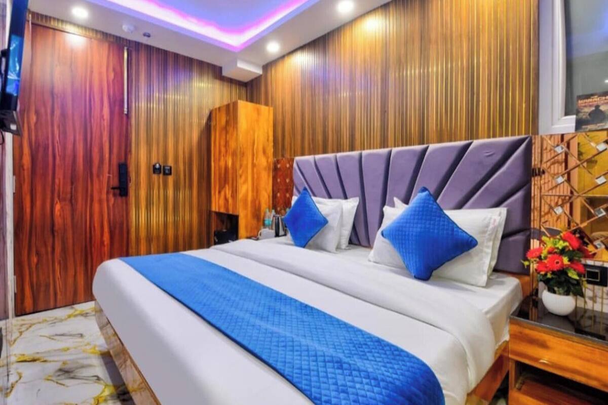 A hotel room with a large bed, wooden panel walls, and a modern ceiling design.