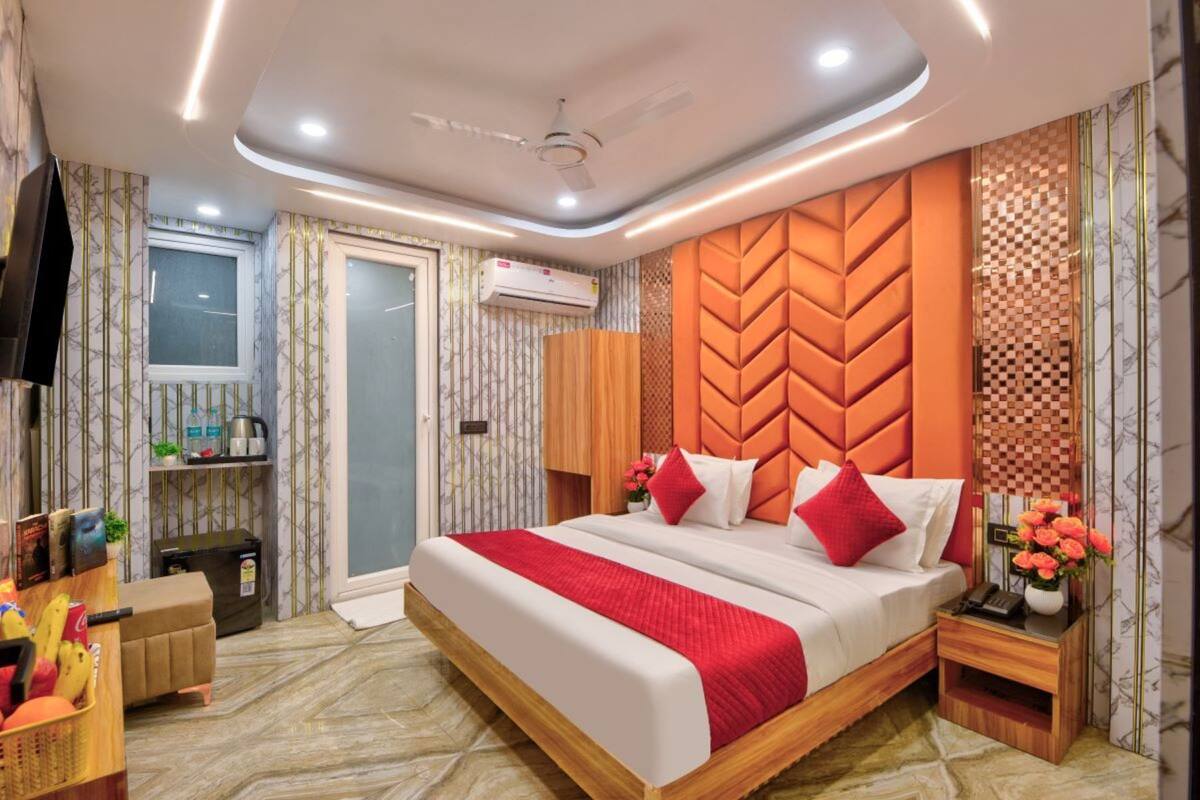 A modern hotel room with a large bed, a wooden headboard, and a ceiling fan. There is a small wooden nightstand with a vase of flowers and a phone.