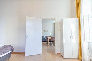 Ein Zimmer mit einem Bett, einem weißen Kleiderschrank und einem Essbereich mit Tisch und Stühlen.