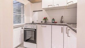 Een keuken met witte kasten, een fornuis, een spoelbak en een raam.