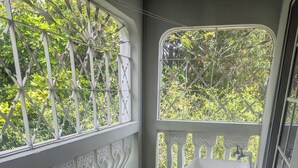 Ein Balkon mit weißer Reling, einem kleinen Tisch und zwei Stühlen.
