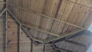 Ein Zimmer mit schrägverdeckter Holzdecke und integrierter Klimaanlage.