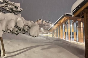 Ein verschneiter Außenbereich mit einem Gebäude, das große Fenster und Holzbalken aufweist.
