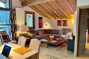 A modern living room with a sofa, chairs, a coffee table, and a laptop on a desk. - Megève 3BR 3BA · Spa, Pool, Fireplace (Megève)