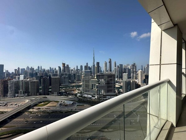 A cityscape with modern high-rise buildings, a prominent tower, and a curved road below. - Burj View 1BR · Pool, Gym & Free Valet (Dubai)