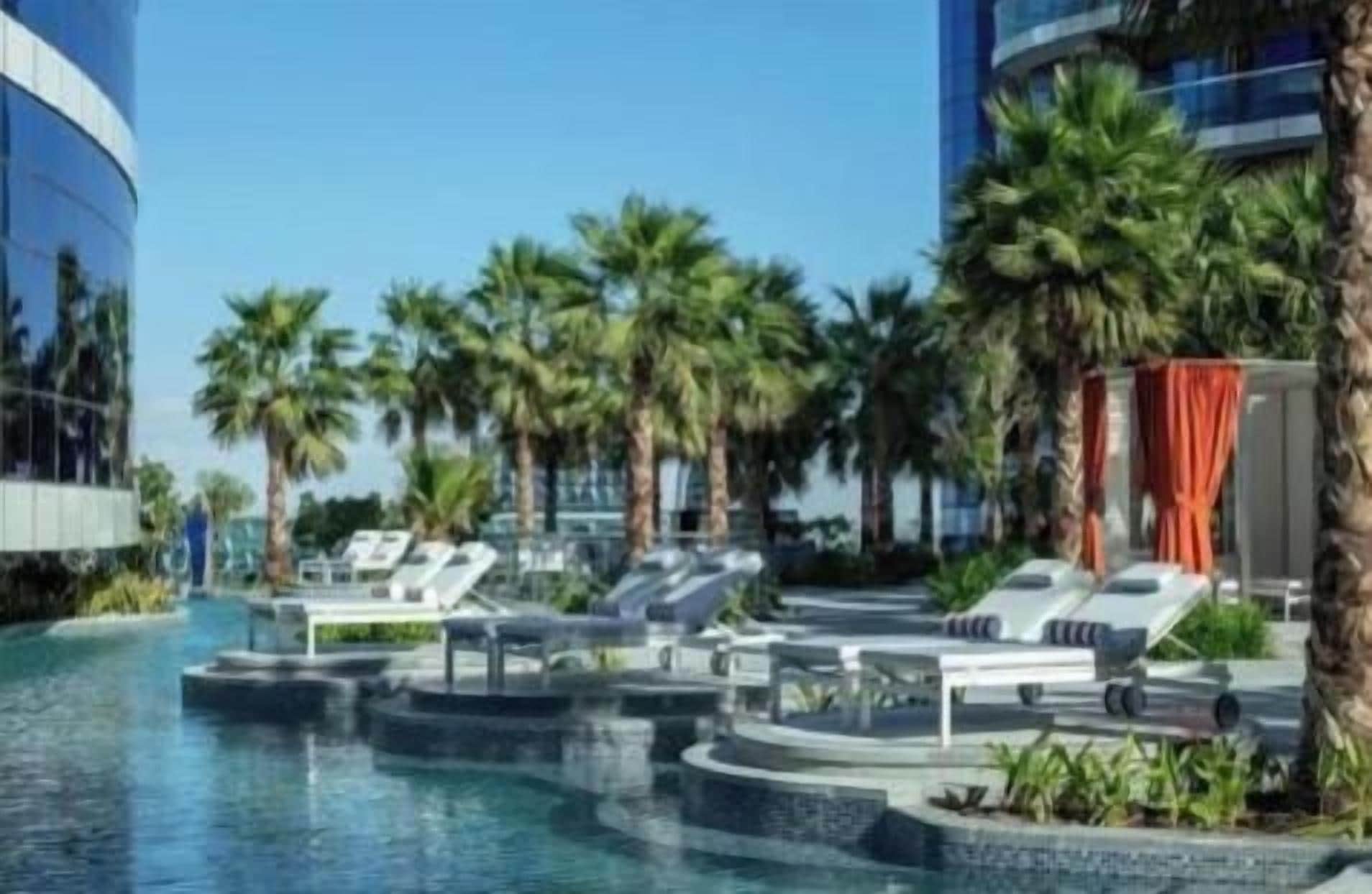 A pool area with lounge chairs and palm trees.