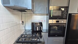 A modern kitchen with a gas stove, a coffee maker, a microwave, and an oven. - Luxury Mombasa Apartment with Ocean and City Views (Mombasa)
