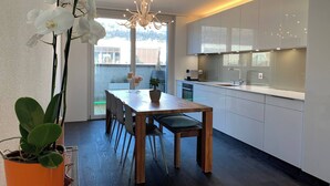 Una cocina moderna con armarios blancos, una mesa de comedor de madera y una planta en maceta.