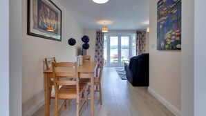 A dining area with a wooden table and chairs, a ceiling light, and a painting on the wall. - Modern Cambridge Home Business & Holiday Stays (Cambridge)