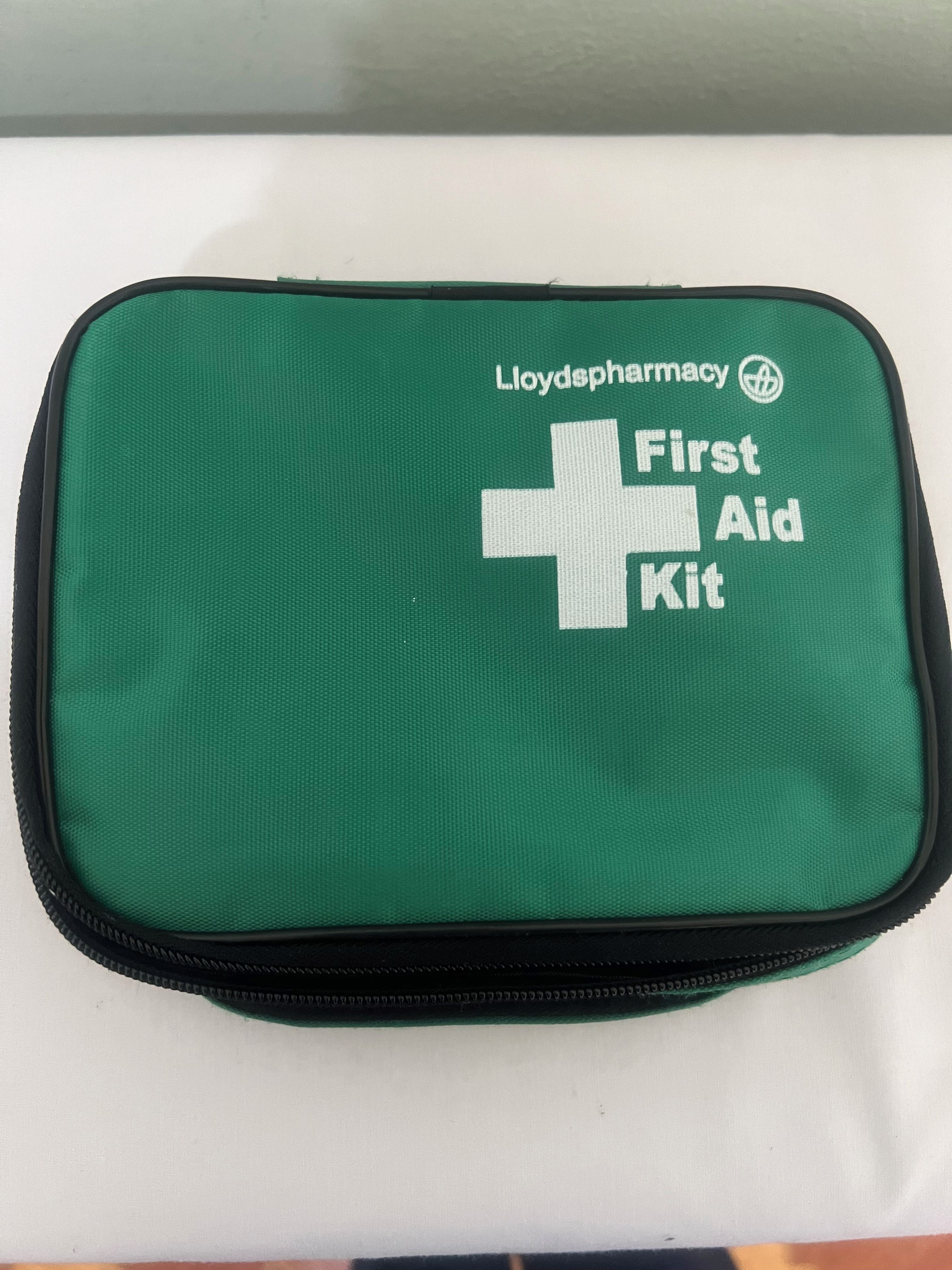 A green first aid kit with the text 'Lloydpharmacy First Aid Kit' on it.