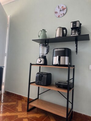 A kitchenette with a coffee maker, a blender, a kettle, and a toaster on a shelf. - Luxury Spacious house up to 09 people on Guaritá Street (Fazenda Rio Grande)