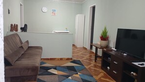 Una sala de estar con sofá, televisión, mesa de centro y alfombra estampada.