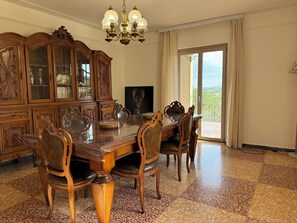 Une salle à manger avec une table et des chaises en bois, un grand buffet et un lustre.
