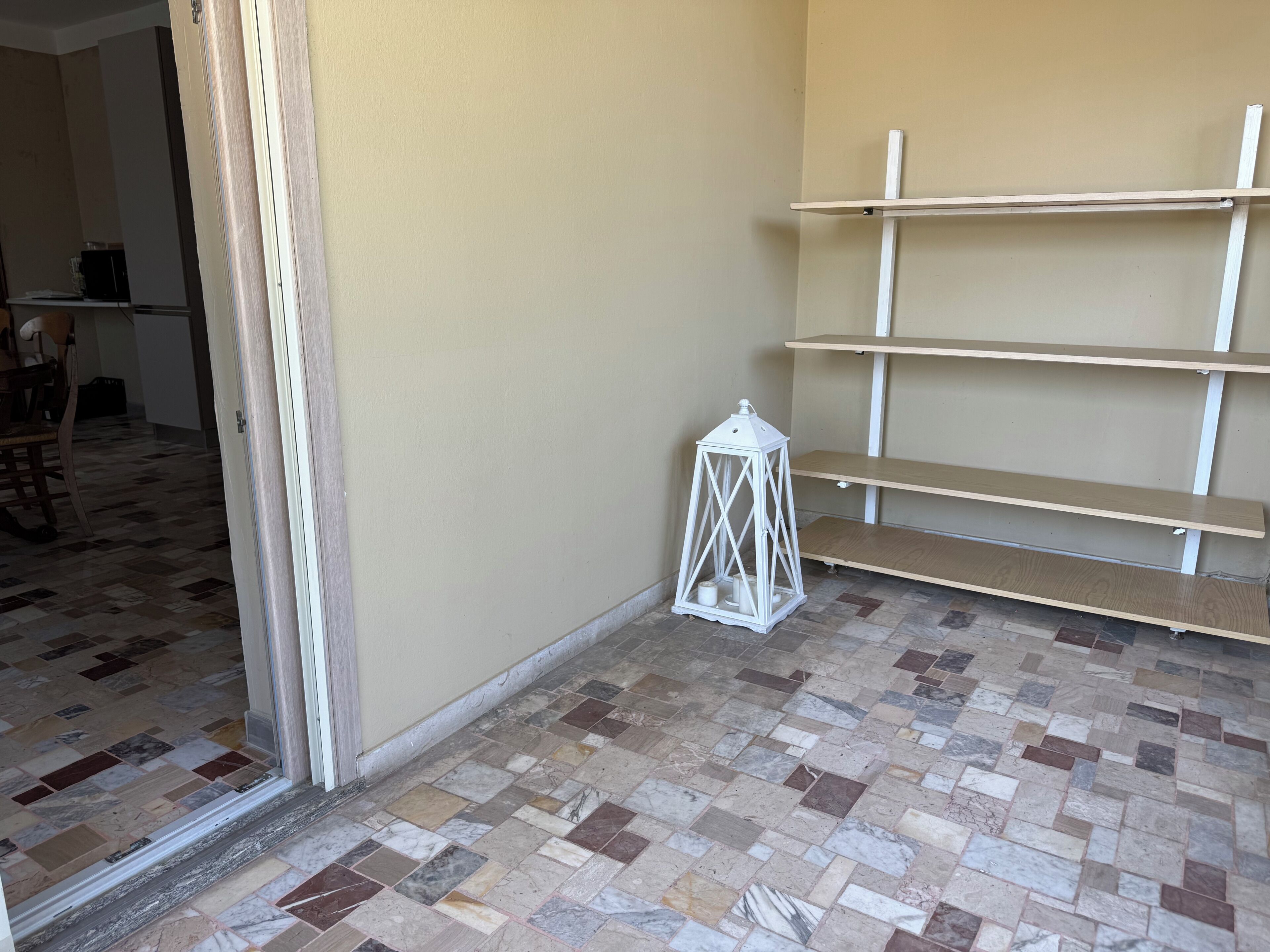 A room with a tiled floor, a white lantern, and wooden shelves against the wall.